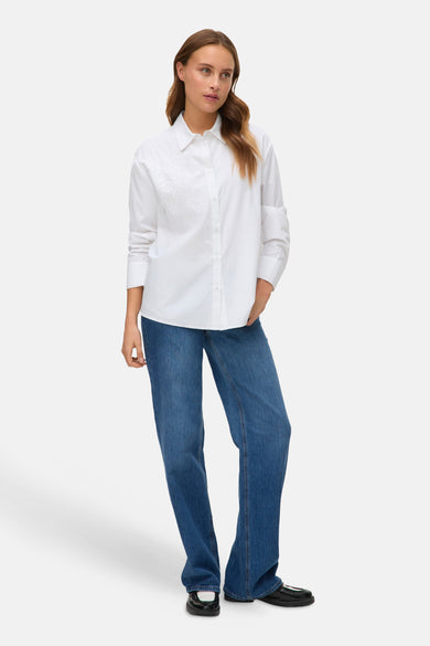 Blanc, chemise à manches longues de VERO MODA avec un motif de feuille subtil, associé à des jeans bleus et des chaussures noires.