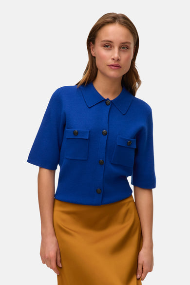 Gilet bleu de VERO MODA, avec des boutons et des poches, associé à une jupe dorée.