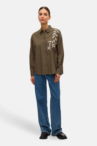 Chemise kaki à manches longues de VERO MODA®, avec une décoration brodée en forme de branches, associée à un jean bleu et des chaussures noires.