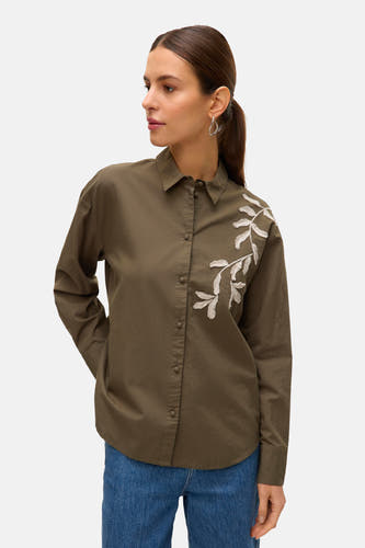 Chemise kaki à manches longues de VERO MODA, avec des branches blanches brodées et portée avec un pantalon de cuir bleu.