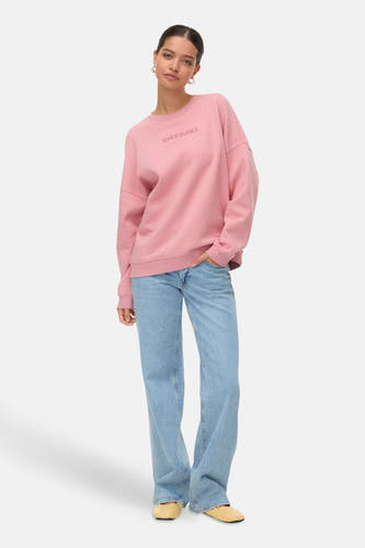 Pull-over rose de VERO MODA, porté avec des jeans bleus et des chaussures légères.