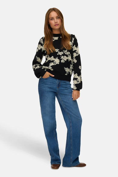 Sweat-shirt noir à col rond de VERO MODA, avec un motif floral et des manches longues, porté avec des jeans.