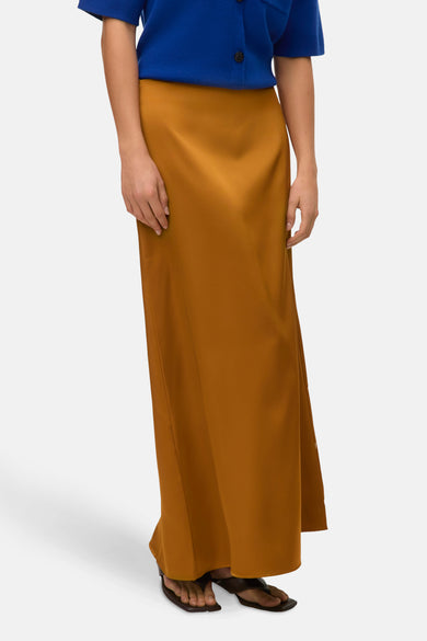 Robe longue dorée de VERO MODA, associée à une veste bleue et des sandales noires.