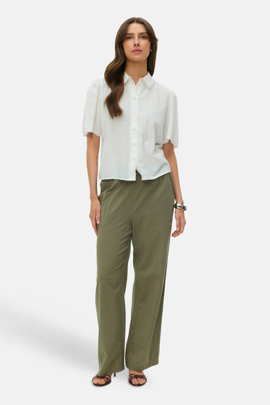 Groene broek van VERO MODA, met wijde pijpen en gedragen met een witte blouse en hakken.
