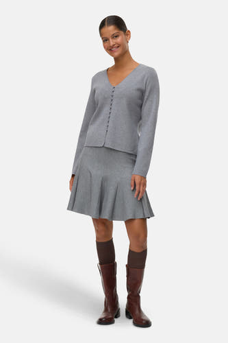 Jupe grise courte de VERO MODA®, associée à des bottes brunes et des chaussettes foncées.