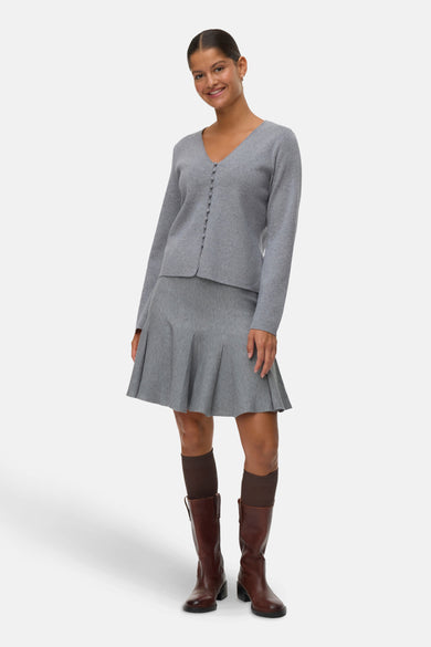Jupe grise courte de VERO MODA®, associée à des bottes brunes et des chaussettes foncées.