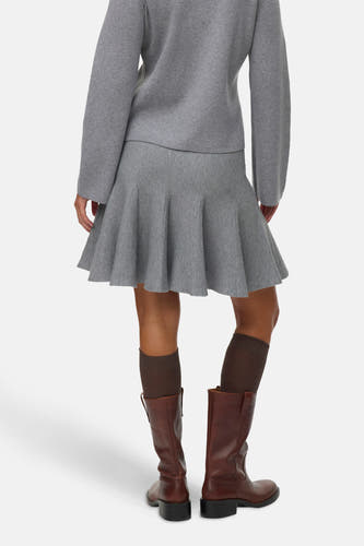 Jupe courte grise de Vero Moda, avec un modèle qui tombe et associée à des bottes brunes et des chaussettes.