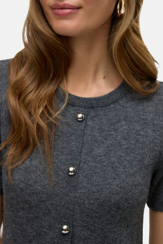 Robe grise à manches courtes de VERO MODA®, avec des boutons argentés et des cheveux blonds ondulés.