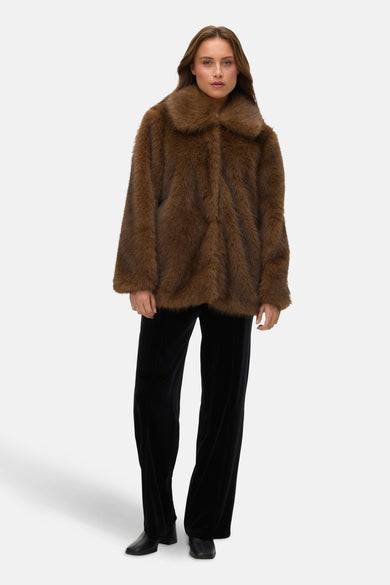 Manteau court brun de VERO MODA, avec col et porté sur une jupe velours noire.