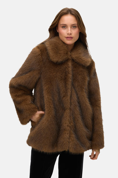Manteau court brun de VERO MODA®, avec une douce texture et un col, porté avec un pantalon noir.
