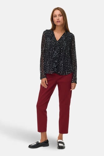 Rode broek van VERO MODA®, gecombineerd met een zwart-witte blouse en zwarte loafers.
