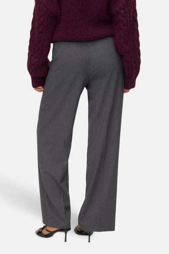 Grijze wijde pantalon en bordeauxrode gebreide trui.