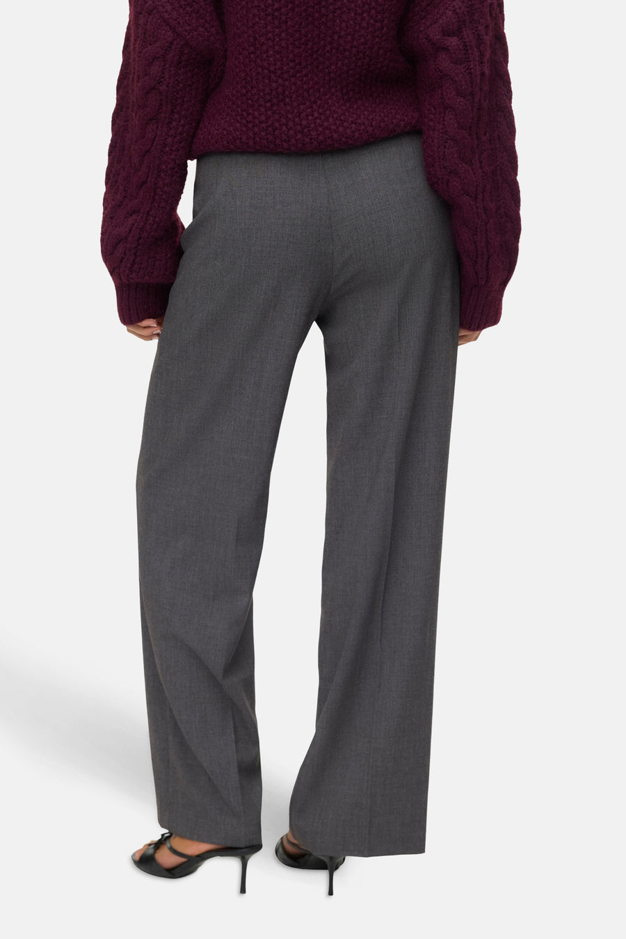 Grijze wijde pantalon en bordeauxrode gebreide trui.