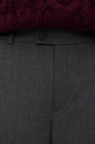 Grijze pantalon met knoop en paarse trui.
