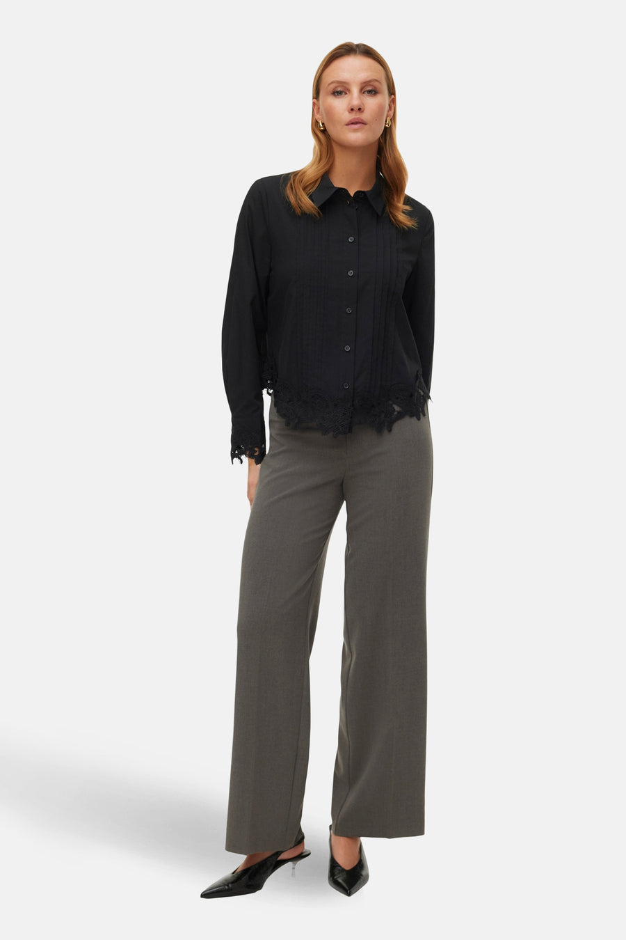 Grijze broek van VERO MODA, met wijde pijpen en gecombineerd met een zwarte blouse en zwarte schoenen.
