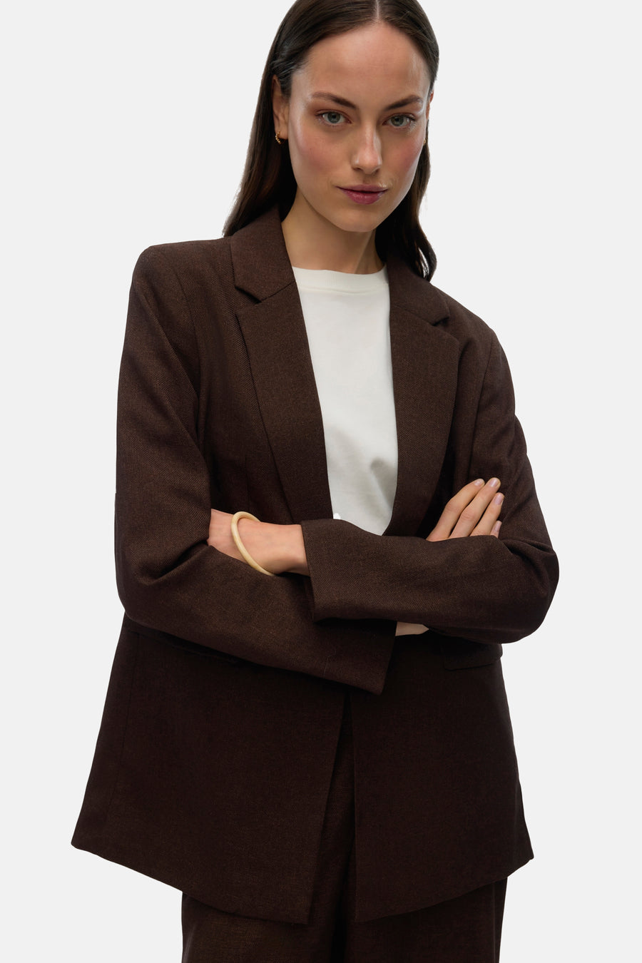 Vrouw in bruin pak met gekruiste armen.