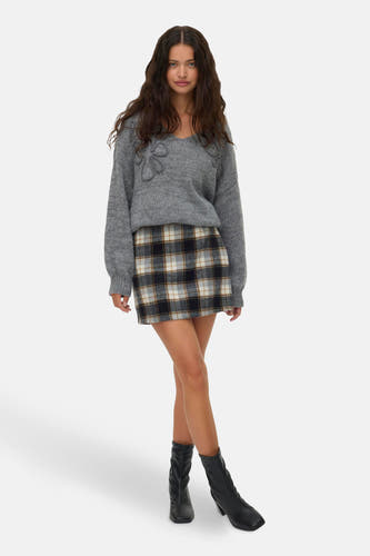 Short skirt with a plaid pattern from Vero Moda, combined with a gray sweater and black boots.
