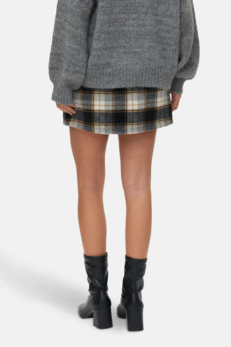 Short skirt with a checkered pattern from VERO MODA, paired with a gray sweater and black boots.