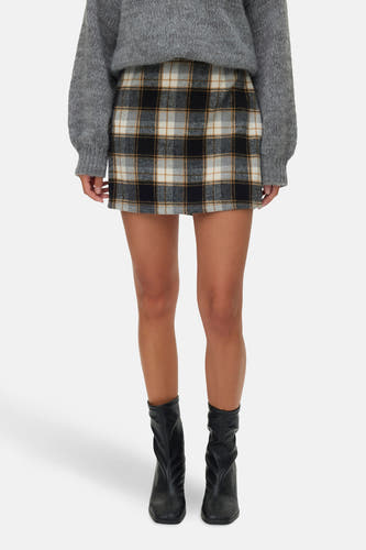 Jupe courte multicolore de VERO MODA, avec motif à carreaux, associée à un pull gris et des bottes noires.
