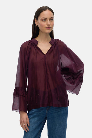 Blouse Bordeaux avec longues manches de VERO MODA, à volants et portée avec un jean bleu.