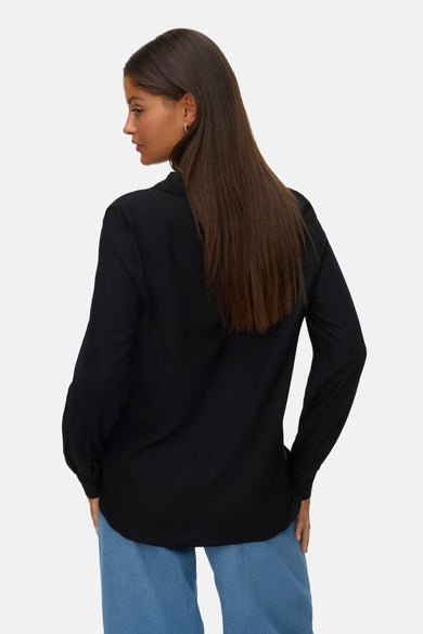 Chemise noire à manches longues de VERO MODA, vue de derrière, associée à un pantalon bleu.