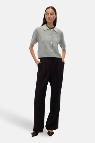 Gilet gris de VERO MODA®, avec des manches courtes, des boutons argentés et porté avec un pantalon noir et des chaussures à boucles.