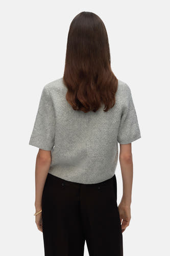 Gilet gris de VERO MODA, vu de de derrière, avec une jupe noire et un bracelet.