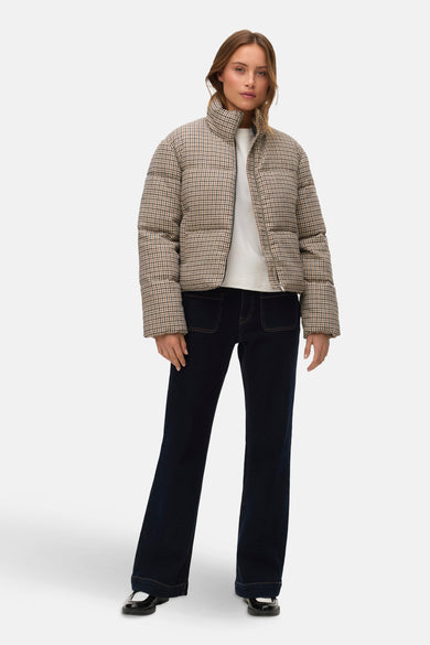 Manteau court beige de VERO MODA, avec un motif à carreaux, porté avec un T-shirt blanc et des jeans foncés.