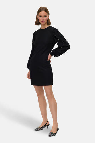 Robe noire à longues manches de Vero Moda, ornée de perles sur les manches, associée à des chaussures noires.