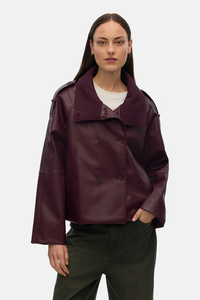 Manteau marron de VERO MODA avec des manches longues, un col en côtes et des doubles boutons, porté sur un T-shirt blanc avec un pantalon vert.