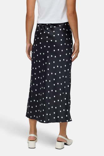 Longue jupe noire de VERO MODA® avec des taches blanches, associée à un t-shirt blanc et à des chaussures écru.