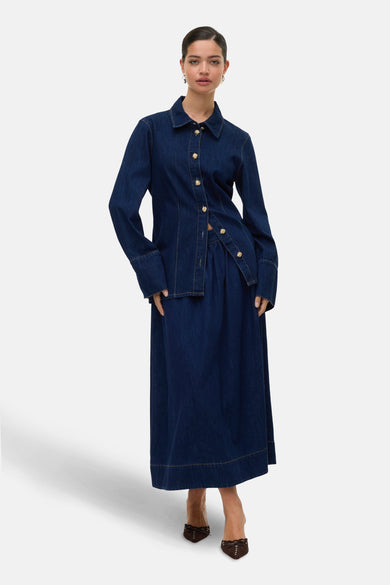 Longue jupe en denim bleu marine de VERO MODA avec des boutons dorés, associée à un chemisier en denim coordonné.