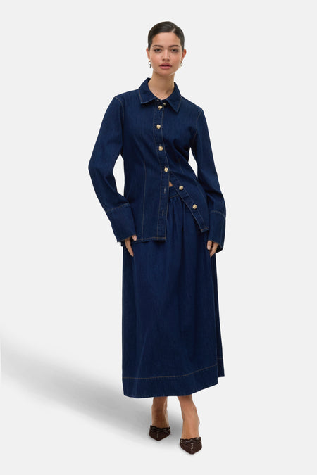 Longue jupe en denim bleu marine de VERO MODA avec des boutons dorés, associée à un chemisier en denim coordonné.