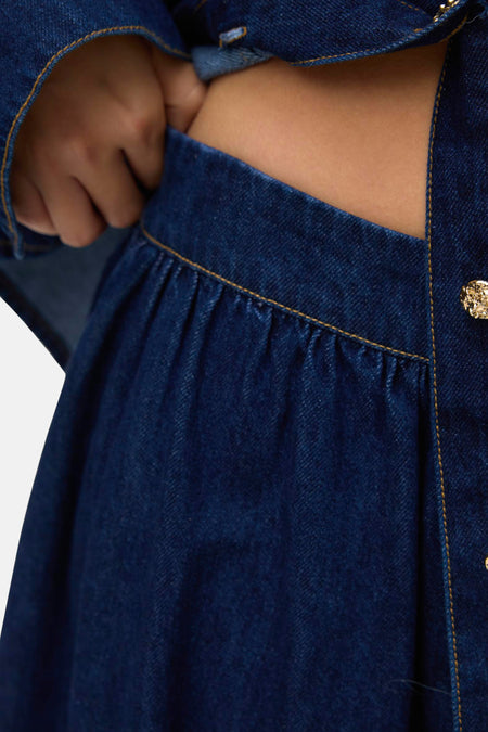 Jupe en denim longue bleu marine de VERO MODA avec plis et bouton doré visible.
