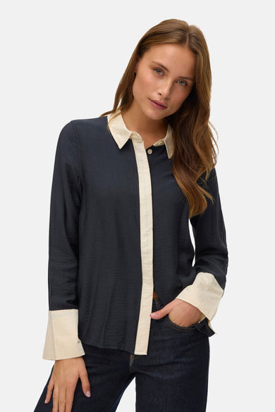 Chemise noire à manches longues de VERO MODA, avec col et poignets contrastants, portée avec un jeans foncé.