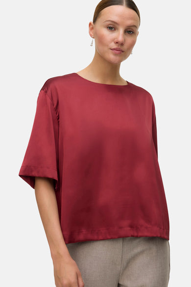 Blouse rouge à manches courtes de VERO MODA, simple et portée avec un pantalon gris.
