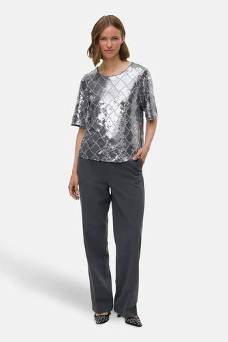 Blouse en argent avec des manches courtes de VERO MODA, ornée de paillettes et d'un motif à carreaux, associée à un pantalon gris.