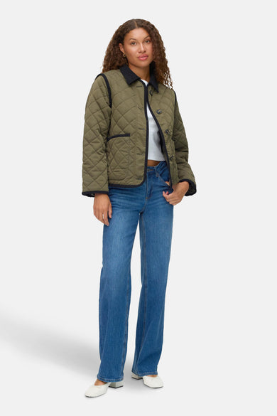 Manteau court vert de VERO MODA, avec des strass et porté avec un t-shirt blanc et des jeans bleus.