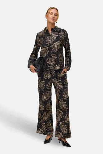 Chemise noire à manches longues de VERO MODA®, avec un motif de feuille dorée et des cheveux relevés.