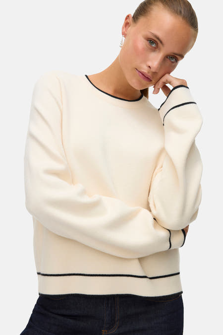 Pull écru à col rond de VERO MODA, avec une patte de boutonnage noire sur la ligne du col, des manches et un ourlet, vu de l'arrière.