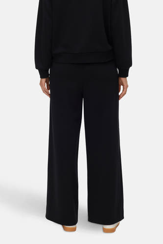 Zwarte joggingbroek van VERO MODA, achterkant, gecombineerd met zwarte sweater en witte sneakers met bruine zolen.
