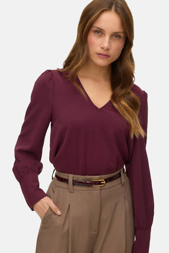 Bordeaux blouse met lange mouwen van VERO MODA®, met V-hals en gecombineerd met een bruine pantalon en riem.