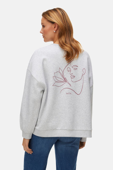 Gilet gris de VERO MODA, avec col rond et texte "Faith", porté avec des jeans et des baskets en argent.