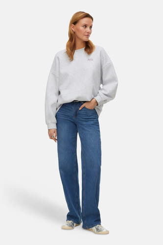 Grijze sweater van VERO MODA, met ronde hals en 'Faith' tekst, gedragen met jeans en zilveren sneakers.
