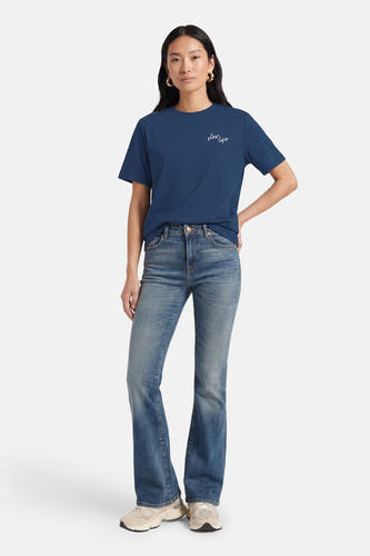 Blauw T-shirt met korte mouwen van VERO MODA® met klein opschrift, gecombineerd met jeans en sneakers.
