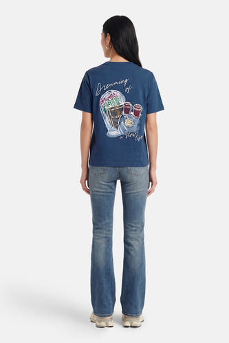 T-shirt bleu à manches courtes de VERO MODA® avec imprimé au dos et porté avec un jean.