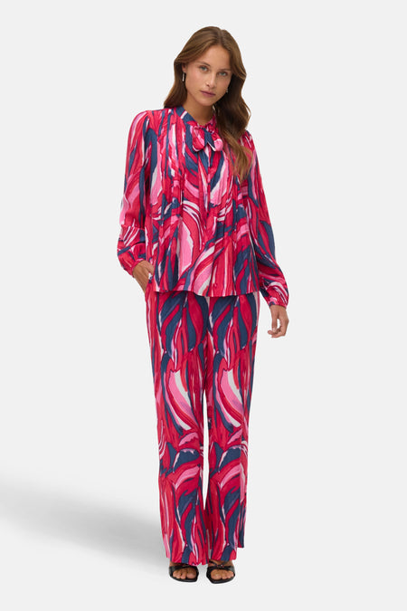 Multikleurige broek van Vero Moda met een opvallend abstract bladmotief in roze, rood en blauw.