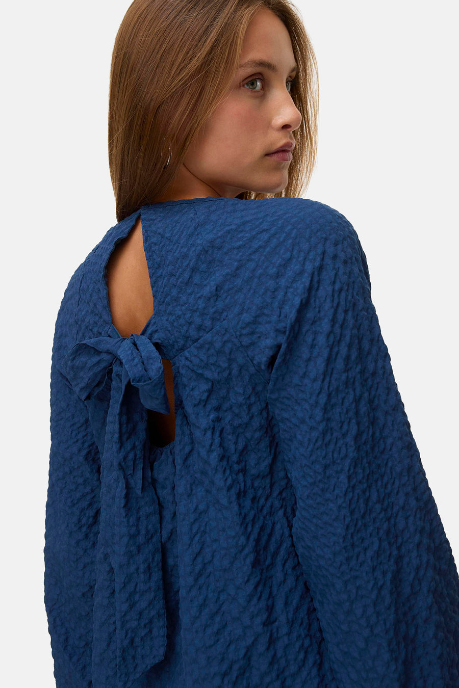 Chemisier bleu à manches longues de VERO MODA®, avec une texture et un détail de nœud à l'arrière.