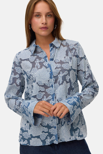 Vrouw draagt blauw-wit gebloemd overhemd.