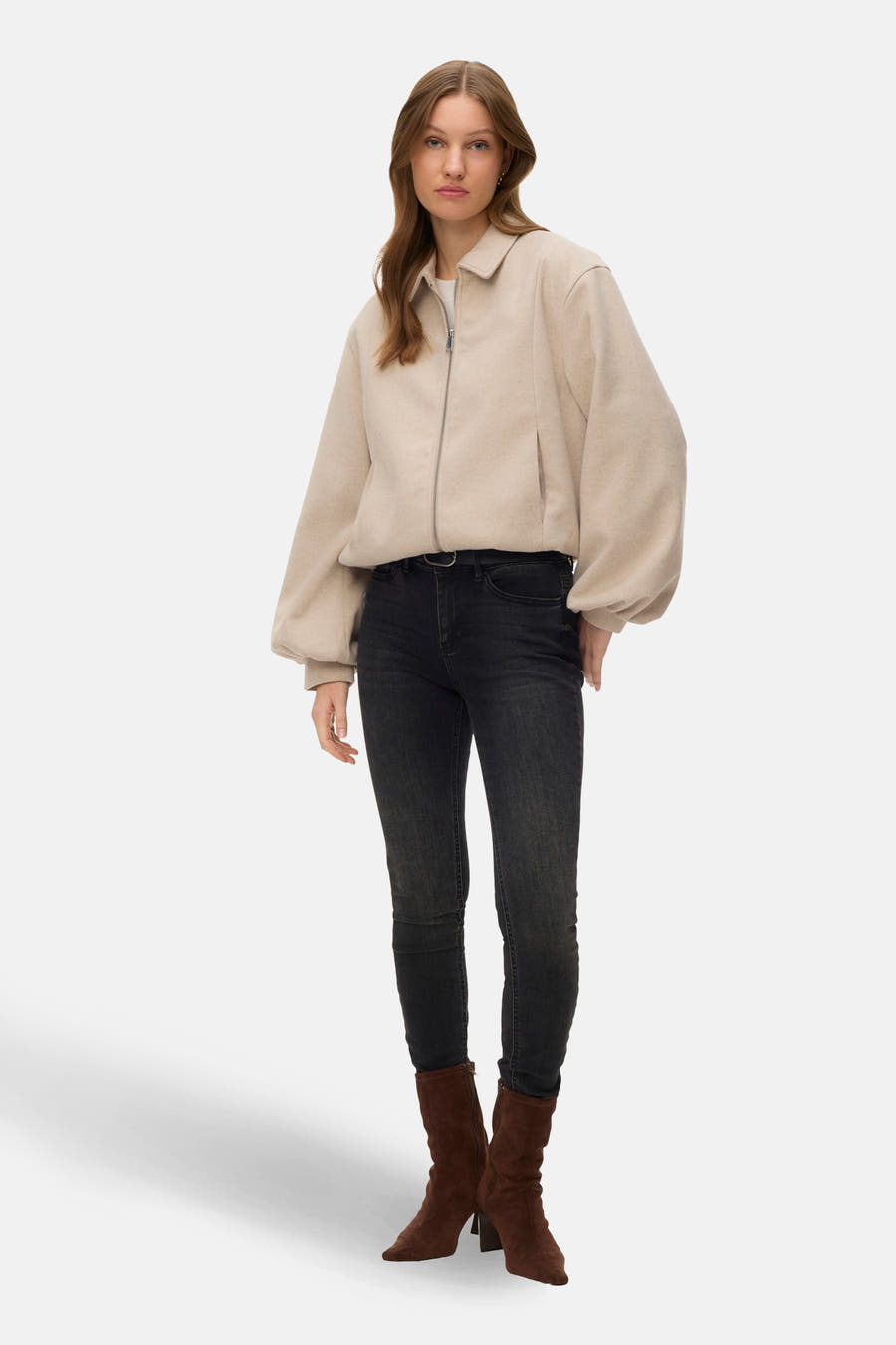 Ecru jas van VERO MODA, met lange mouwen en een ritssluiting, gecombineerd met zwarte jeans en bruine laarzen.